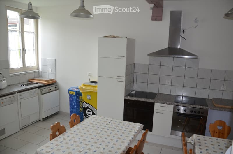 Modern kitchen with white cabinets, stainless steel appliances, granite countertops, and a dining area with a table and chairs.