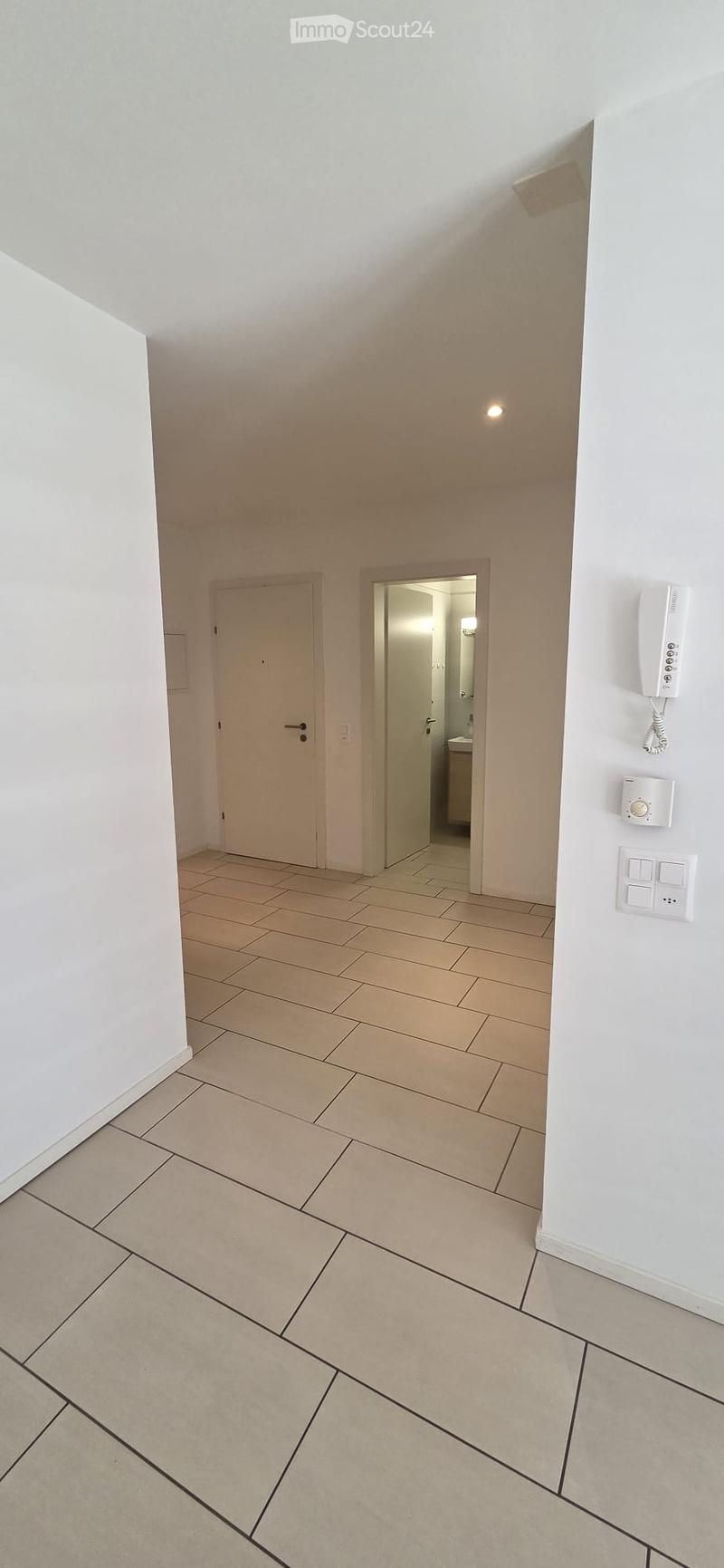 Empty hallway with tiled floor, white walls, and two doors leading to other rooms.