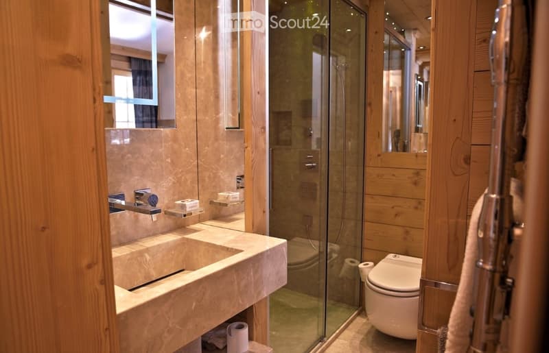 Modern bathroom with a double sink, toilet, glass-enclosed shower, and wooden accents.