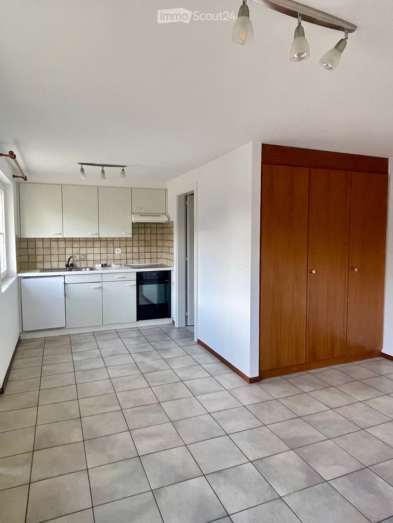 Empty kitchen with white cabinets, tiled floor, sink, and oven. No appliances or items are present.