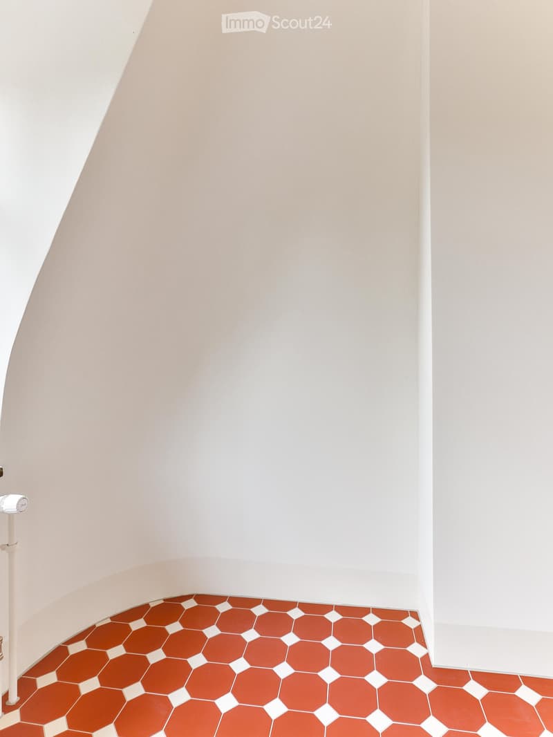 Empty room with white walls and a red hexagonal tile floor. No furniture or equipment visible.