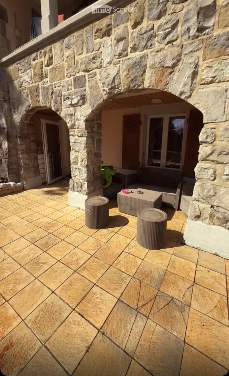 Outdoor patio with stone walls, tiled floor, and outdoor furniture including a table, chairs, and stools.