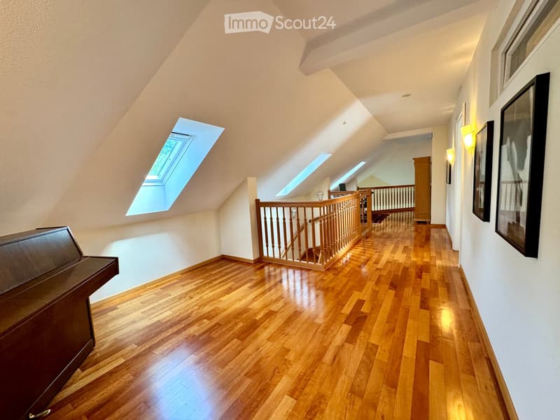 large room with wooden flooring, wall-mounted pictures, piano, open attic space, loft