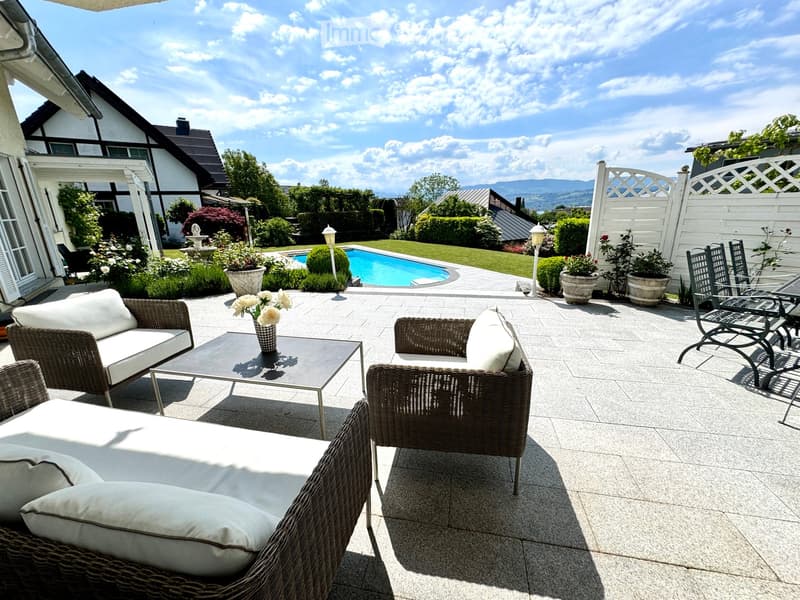 Large outdoor seating area with wicker furniture, pool, garden, fence