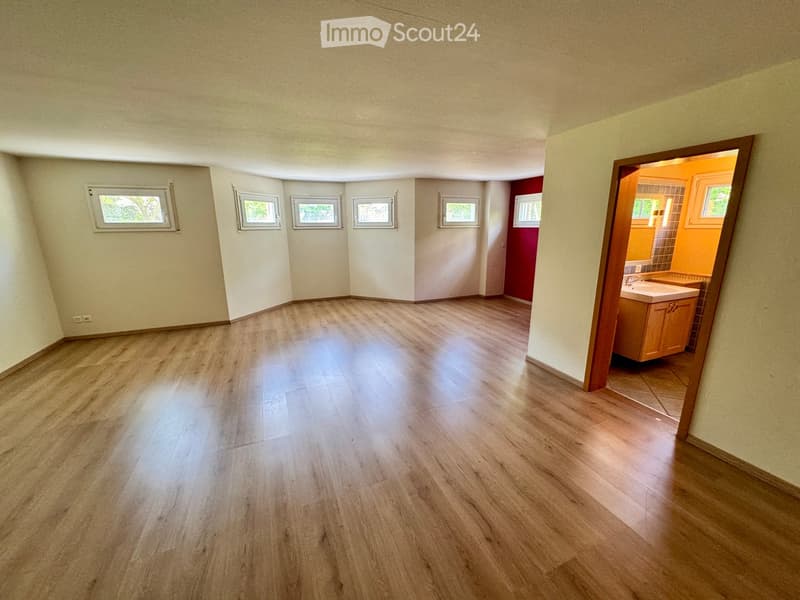 empty room with wooden floor, white walls, six windows, doorway to bathroom