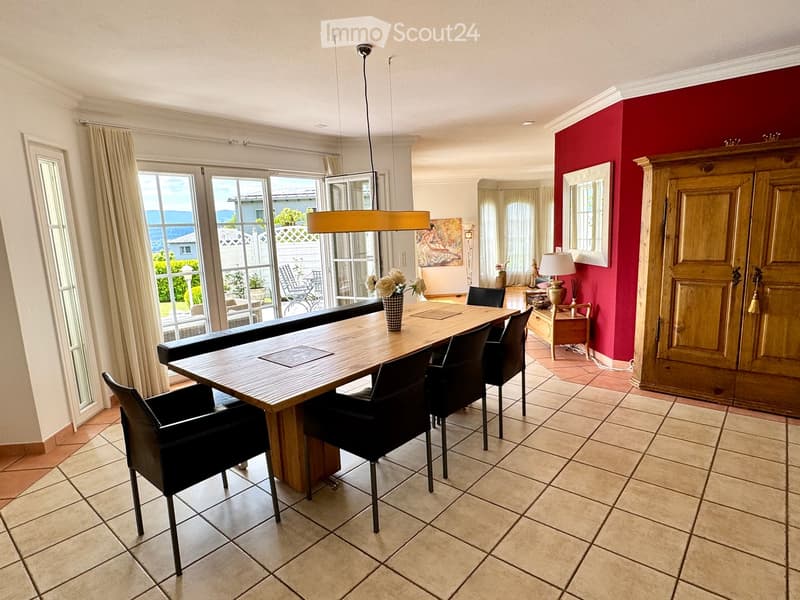 Dining area with wooden dining table, black chairs, and large glass doors leading to a patio with a view