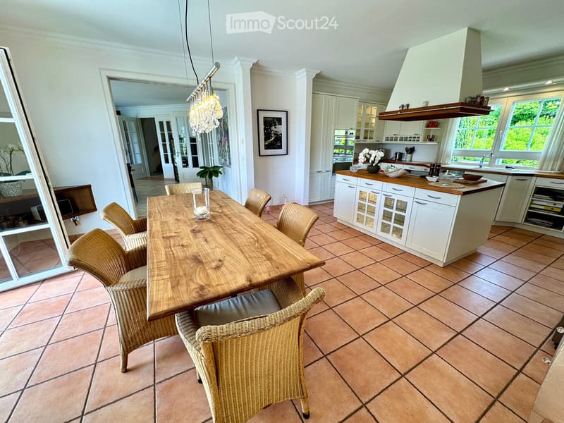 dining room with wooden dining table and wicker chairs, chandelier, kitchen island with bar seating, open cupboards, island countertop, open shelves, dining island with large windows