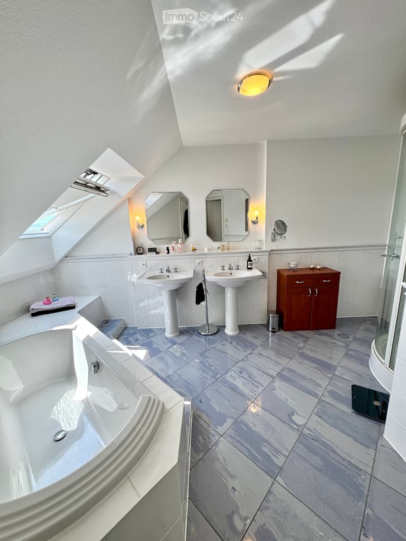 Bathroom with bathtub, dual sinks, shower, wooden vanity, mirrors, ceiling light