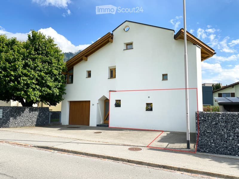 Two-story white house with wooden garage door, small windows, and decorative flower boxes.