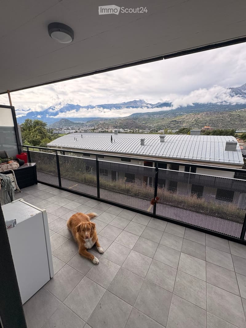 Balcony with tiled floor, metal railing, and scenic mountain view in the background.