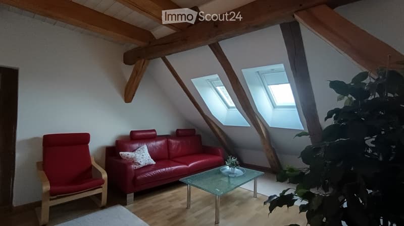 Attic room with wooden beams, red sofa, white coffee table, red chair, white rug