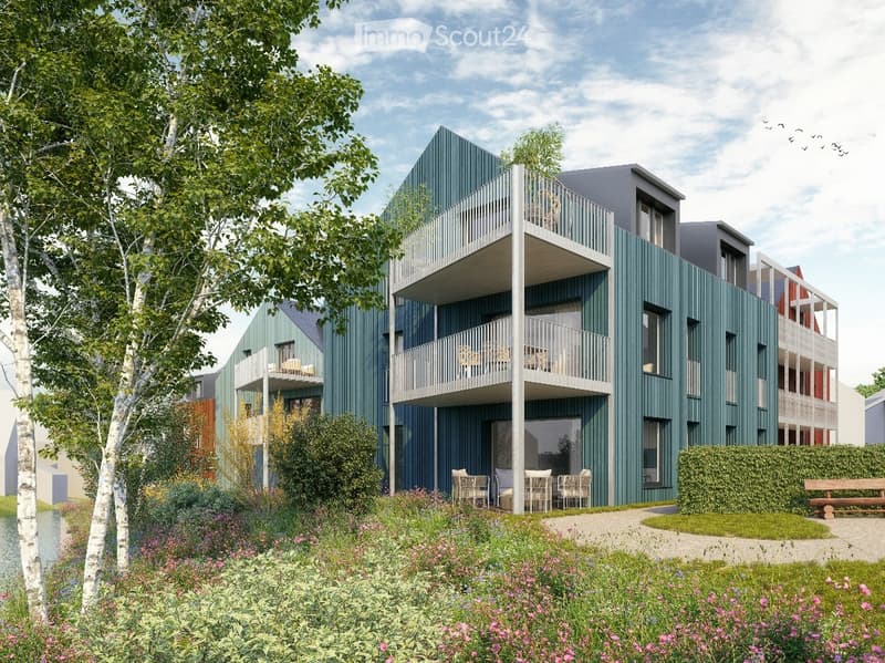 Modern multi-story residential building with green siding, balconies, and outdoor seating areas.
