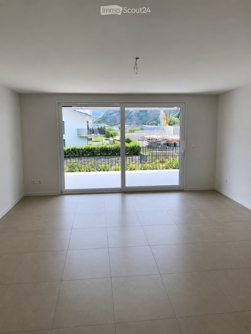 Empty room with tiled floor, large sliding glass doors leading to a balcony, and white walls.
