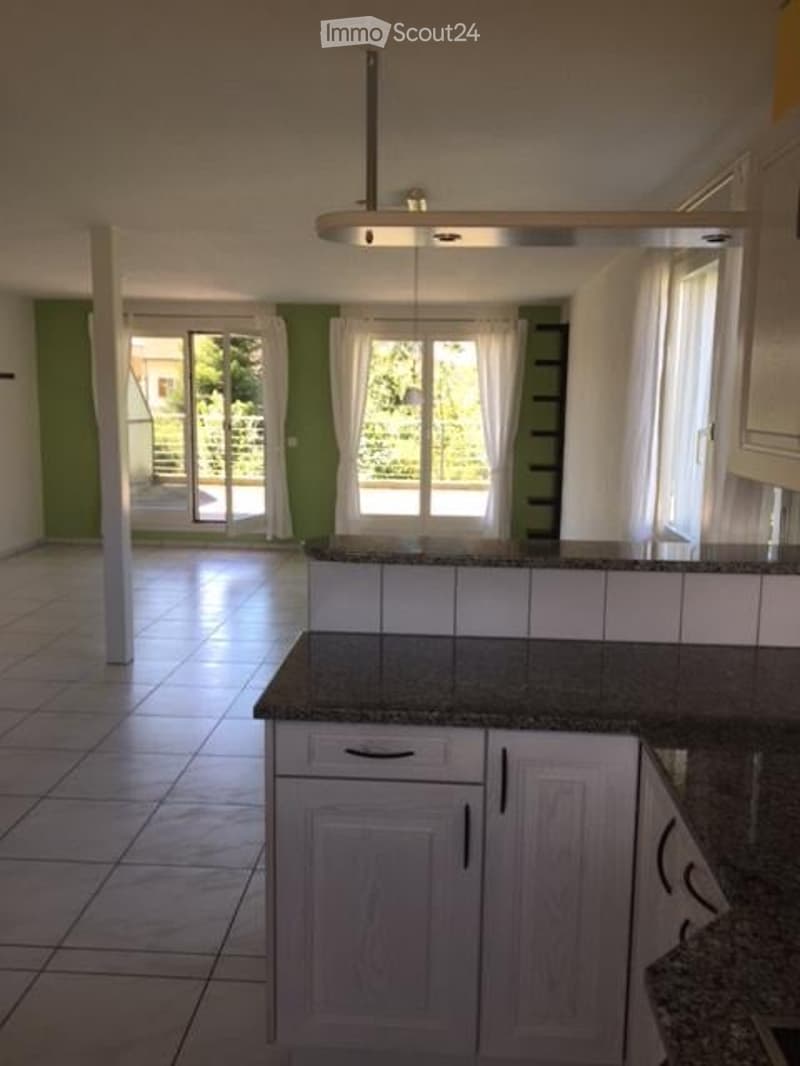 Bright kitchen with white cabinets, granite countertop, and large windows offering a view of the garden. A pendant light hangs from the ceiling.