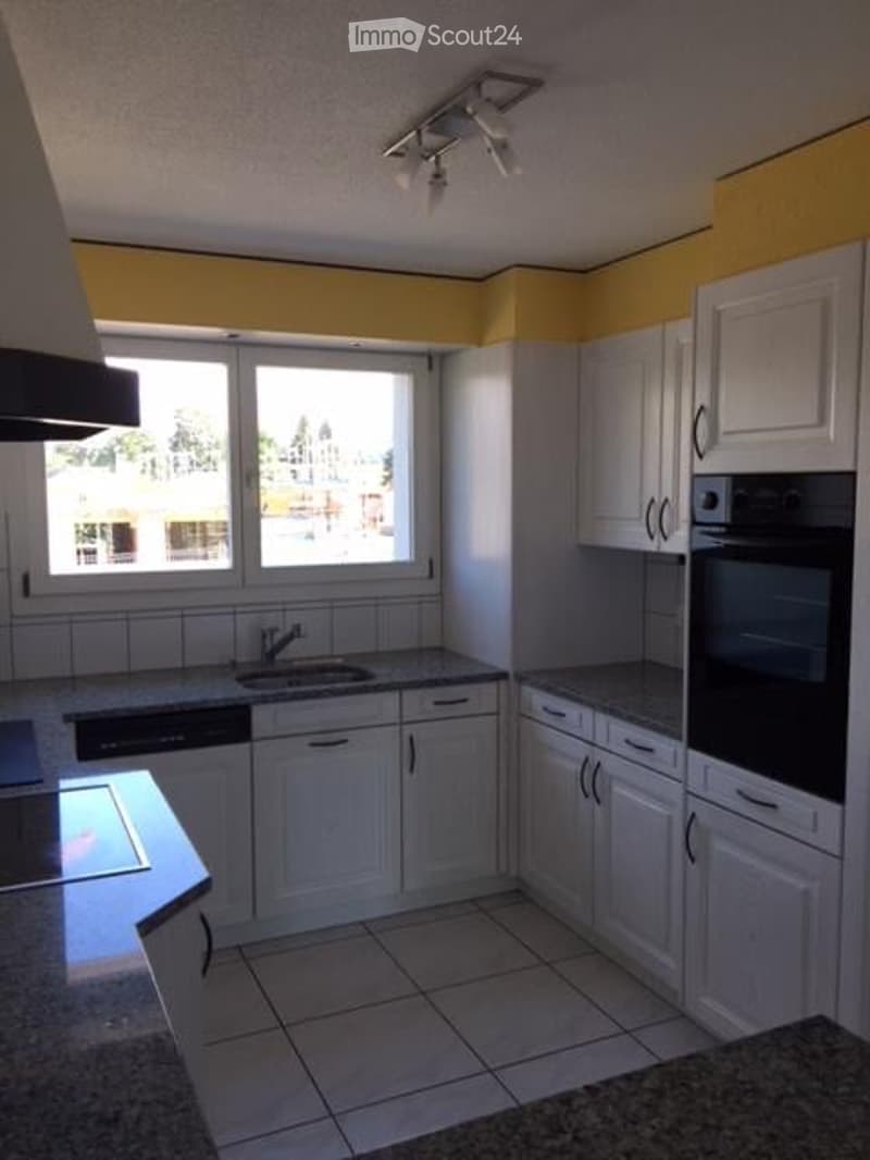 Bright kitchen with white cabinets, granite countertops, and a large window offering a view. Includes a sink, faucet, oven, and dishwasher.