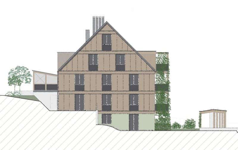 The building has three floors with multiple windows and a triangular roof. The facade is made of wooden panels with a brown color. There are trees in front of the building and an auxiliary building on the right side.
