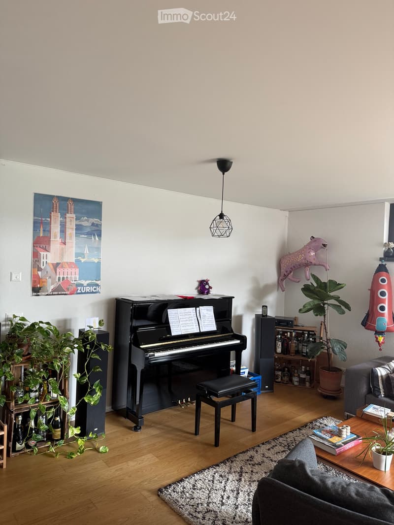 A modern living room with a grand piano, a sofa, a coffee table, and various decorative items including plants, balloons, and a poster.