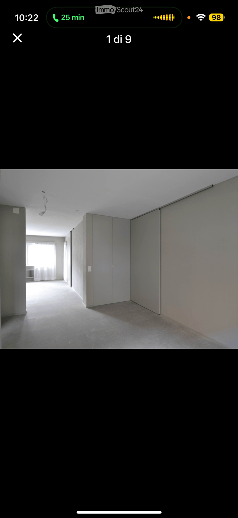 Empty room with tiled floor, grey walls, and a window with white curtains in the background.