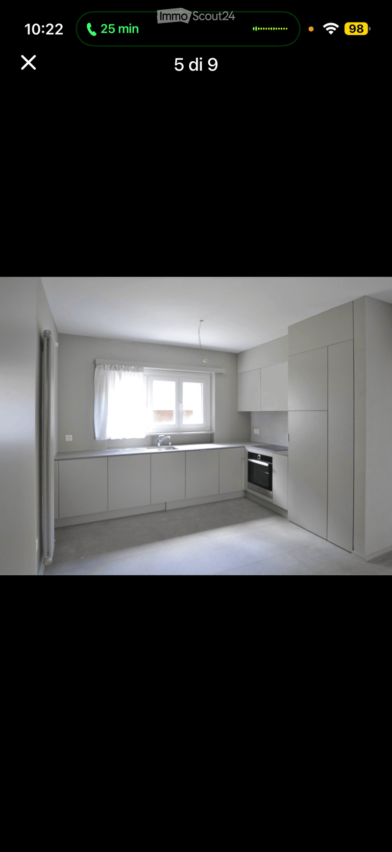 Modern kitchen with white cabinets, a sink, and an oven, featuring a window with a curtain.