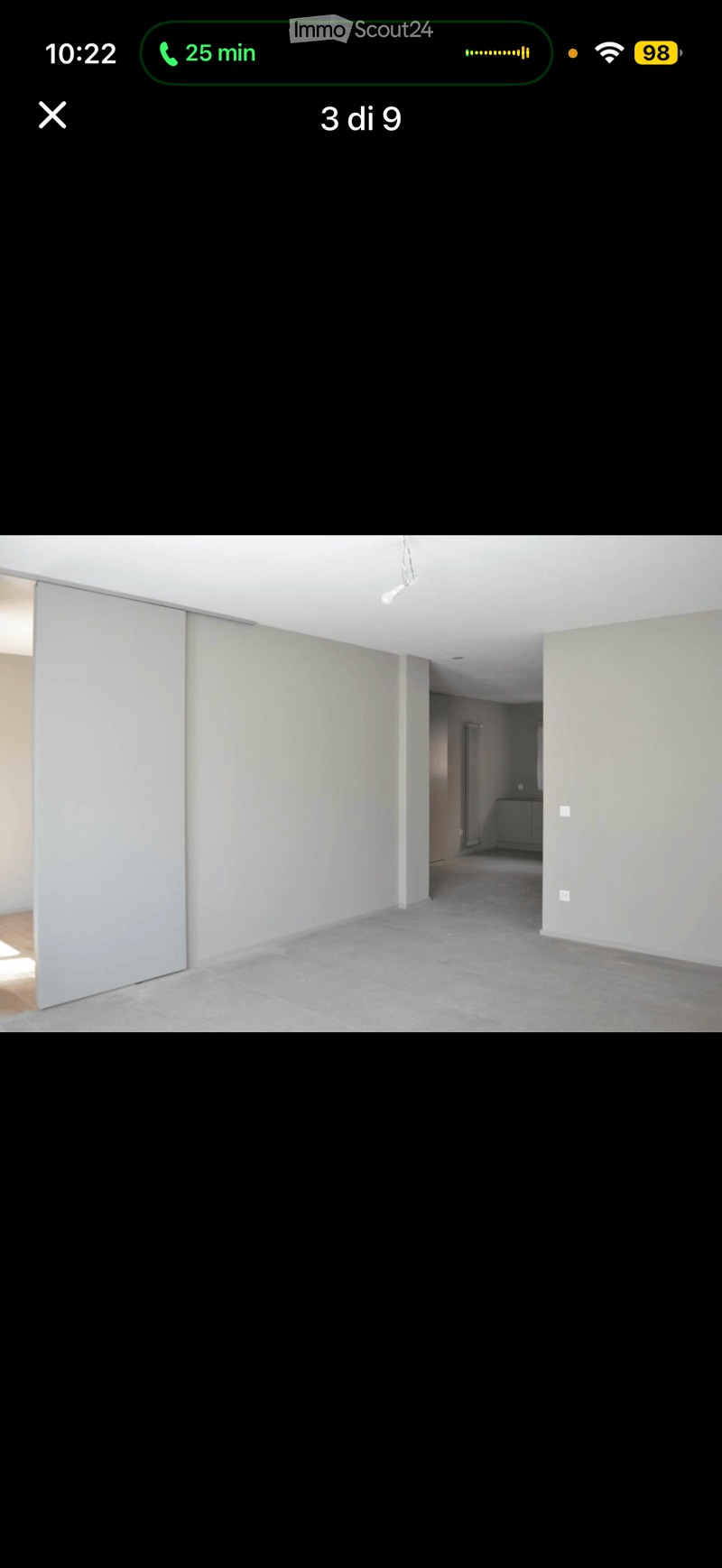 Empty room with light-colored walls, grey tiled floor, and a sliding door leading to another area.