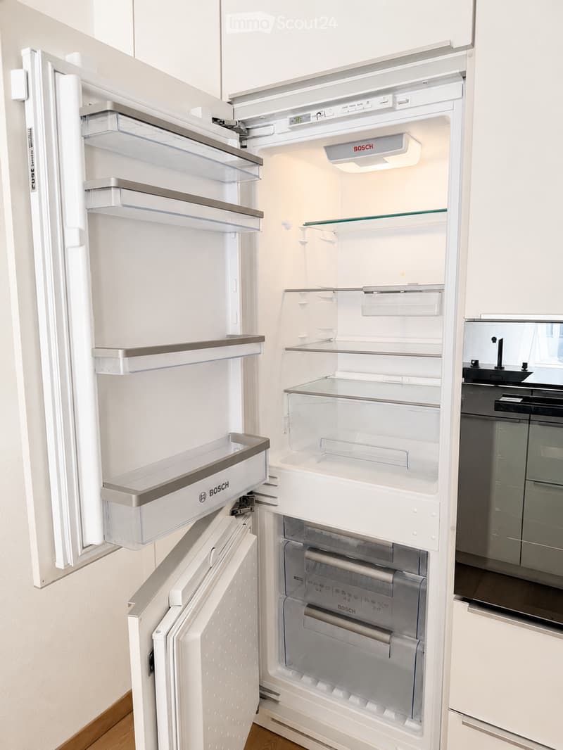A modern, white Bosch refrigerator with multiple compartments and shelves, fully open, showing a clean and organized interior.