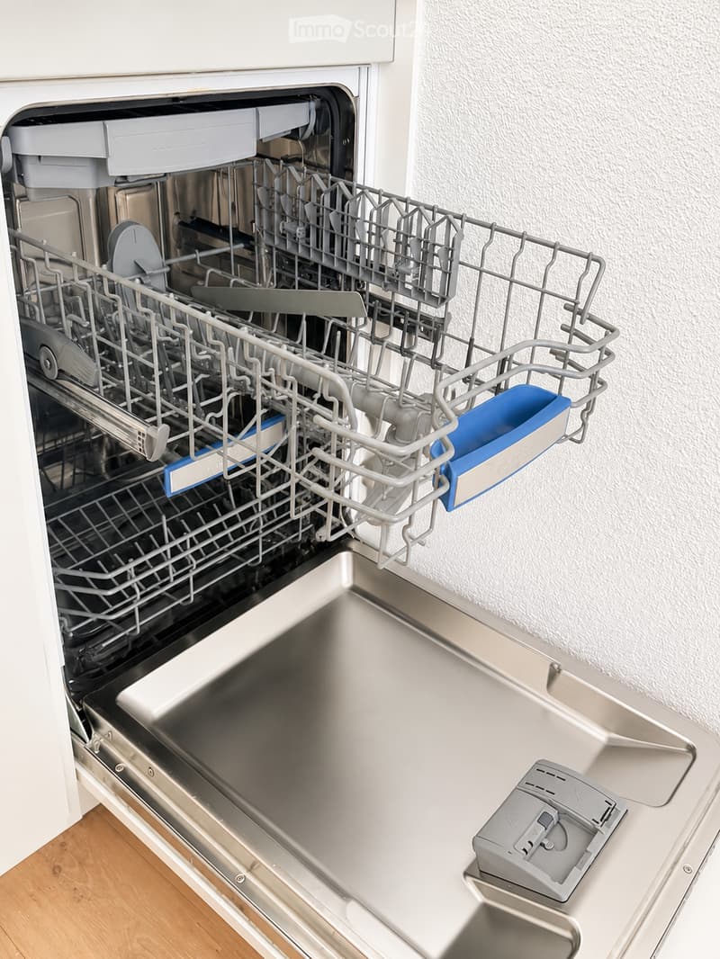 Open stainless steel dishwasher with multiple racks and a control panel visible.