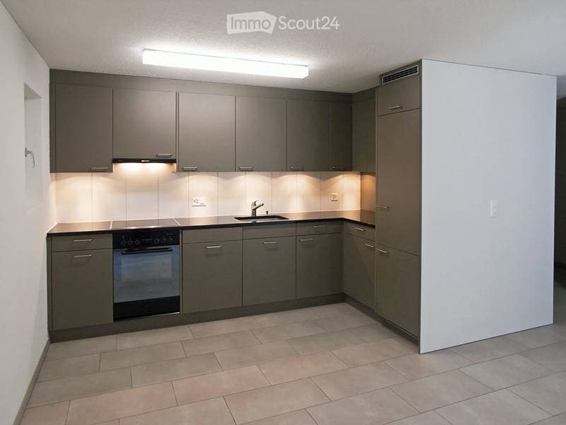 Modern kitchen with grey cabinets, a built-in oven, a sink with a faucet, and integrated lighting under the cabinets.