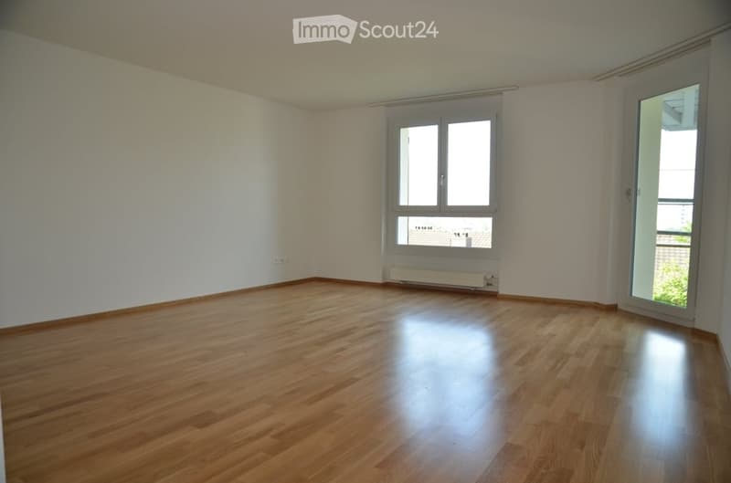 Empty room with wooden flooring, white walls, and large windows with blinds. No furniture or equipment present.