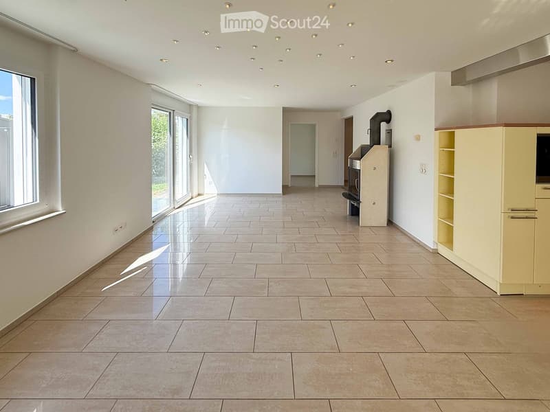 Empty room with tiled floor, white walls, large windows, and a small cabinet in the corner.