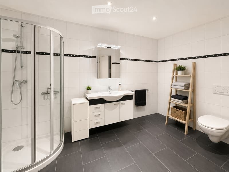 Modern bathroom with white tiles, dark grey floor tiles, a glass-enclosed shower, a white sink with a mirror, a toilet, a small cabinet, and a wooden shelf with towels and a plant.