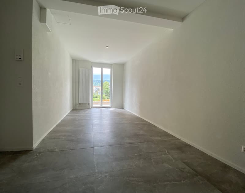 Empty hallway with tiled floor, white walls, and a large sliding glass door leading to an outdoor area.