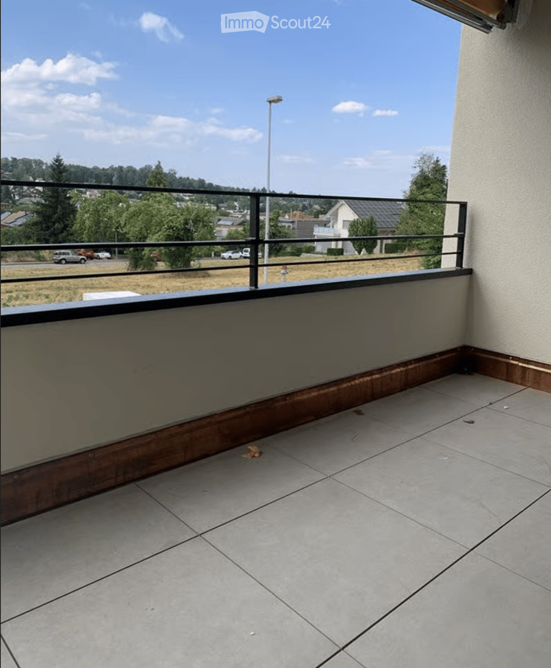 Balcony with tiled floor, wooden trim, metal railing, and a view of the surrounding area.