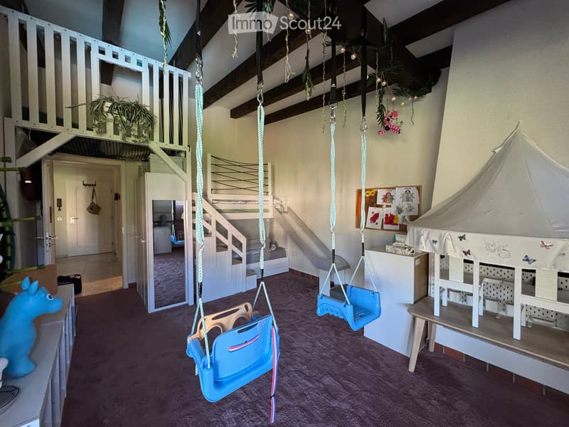 A well-lit children's play area with a swing, toy horse, playhouse, bunk bed, and a small staircase leading to an upper level.
