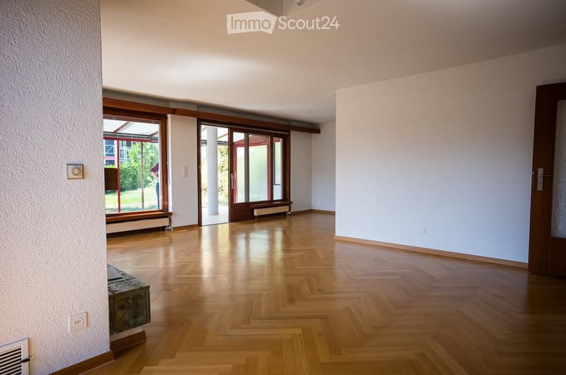 Empty room with wooden flooring, large sliding glass doors leading to an outdoor area, white walls, and minimal furnishings.