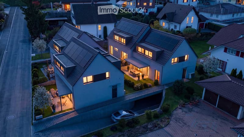 Aerial view of a residential neighborhood with modern houses, solar panels, garages, and well-maintained gardens.