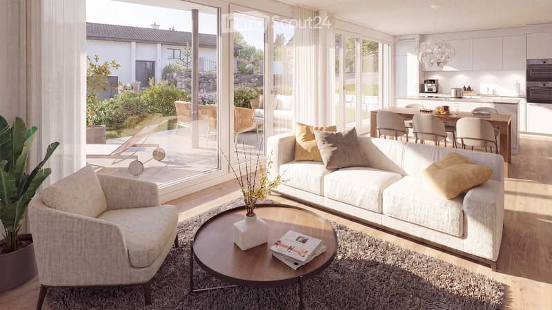 Modern living room with a white sofa, coffee table, armchair, and a view of the garden through large windows. The room is well-lit with natural light and features a cozy rug and decorative pillows.