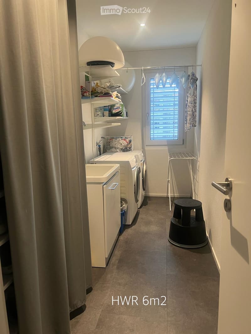 Laundry room with a washing machine, dryer, shelf, and a small window with blinds.