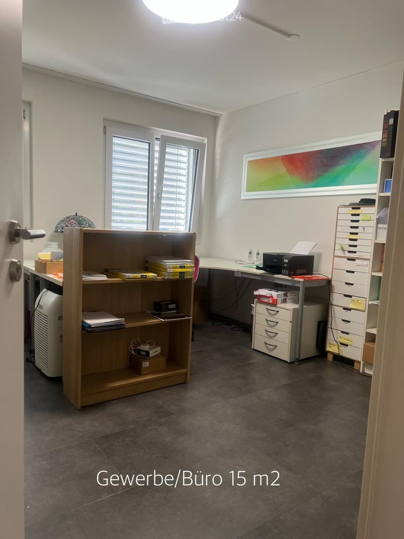 Office space with a desk, chair, printer, cabinet, drawer unit, bookshelf, lamp, and a framed picture on the wall.