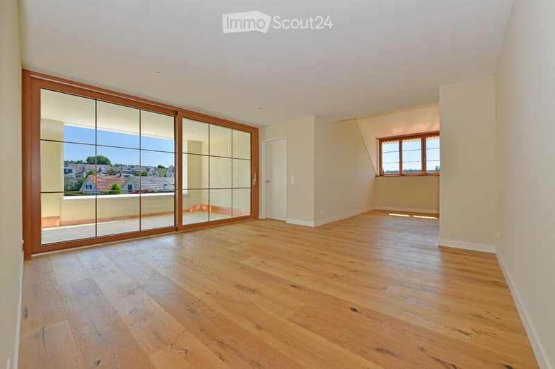 Empty room with wooden flooring, large sliding glass doors leading to a balcony, and a window with wooden frames.