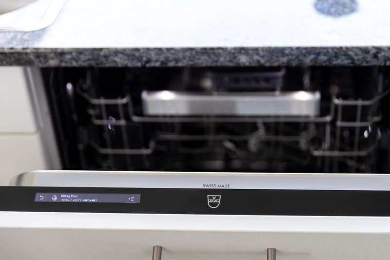 Modern kitchen with a stainless steel dishwasher featuring a digital display and control panel.