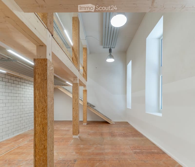 Modern hallway with wooden floors, exposed wooden beams, white walls, and a staircase leading to an upper level.