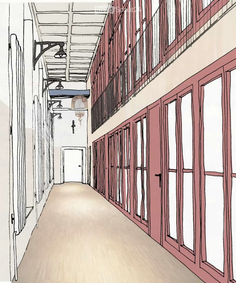 A long, narrow hallway with wooden flooring, exposed wooden beams on the ceiling, and several doors on both sides. The hallway features wall-mounted lighting fixtures and a chandelier hanging from the ceiling.