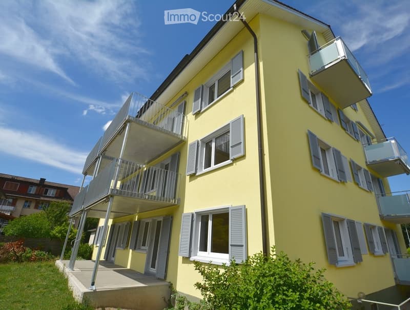 Four-story yellow building with multiple balconies and white shutters on windows.