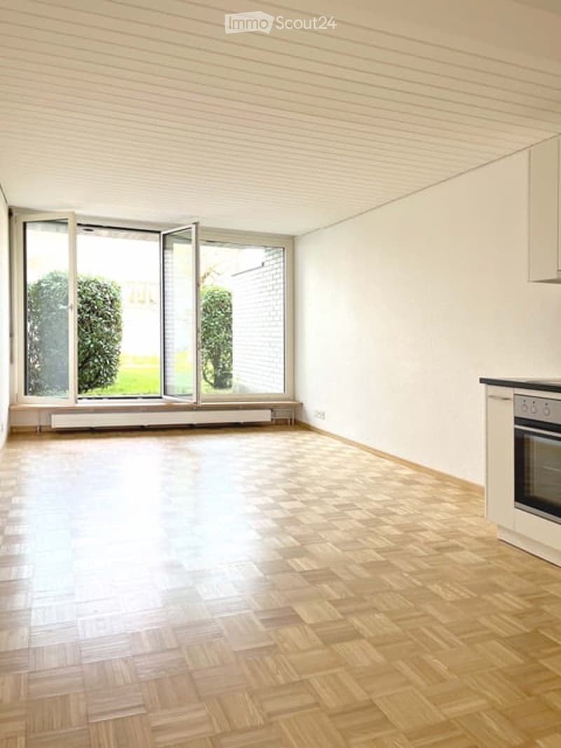 Empty room with wooden flooring, large windows, and white walls. No furniture or equipment present.