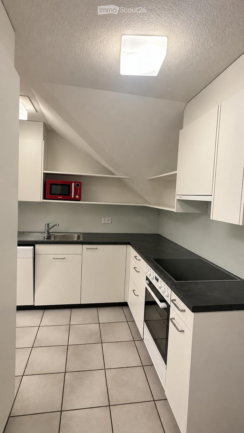 Modern kitchen with white cabinets, black countertops, and tiled flooring. Features a microwave, sink, stove, and oven.