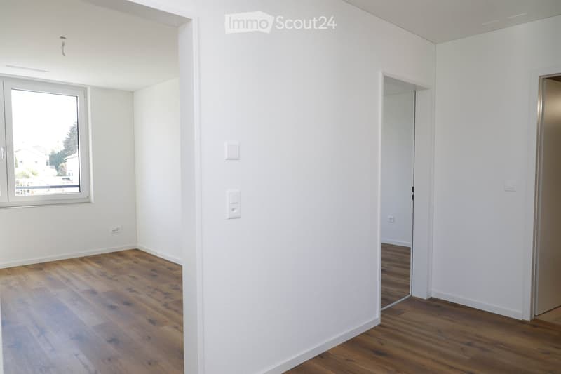 Empty room with white walls, wooden flooring, and a window with a view of the outside. No furniture or equipment is present.
