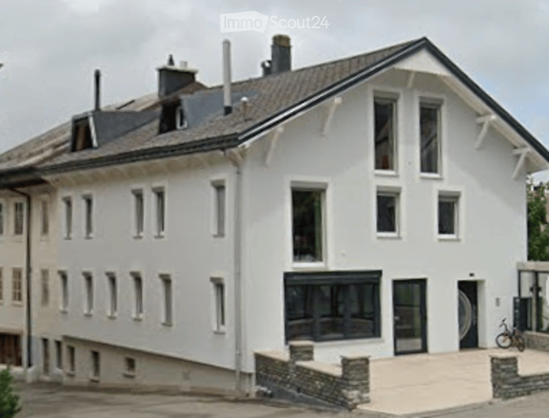 Modern two-story white house with multiple windows, flat roof, and stone foundation.