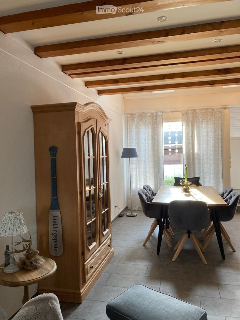 Dining room with wooden cabinet, dining table, chairs, lamps, and decorative items.
