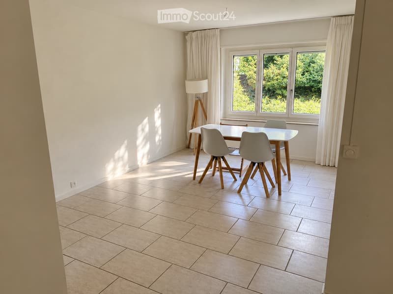 Bright dining room with tiled floor, large window with curtains, modern white dining table and chairs, and a floor lamp near the window.