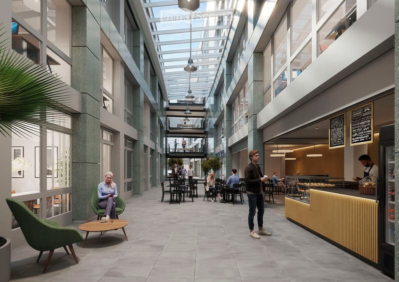 Modern, open-plan lounge area with a mix of seating, tables, and a coffee bar. The space features contemporary furniture, large windows, and a high ceiling with exposed lighting fixtures.